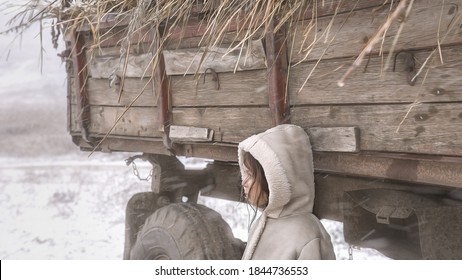 A Girl In A Warm Fur Coat And A Hood Standing By A Big Car And Looking At A Snowstorm. Image With Selective Focus And Noise Effects And Toning