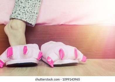 Girl In Warm Pajama Wearing Cute Pink Monster Foot Slippers With Big Claws In The Morning.