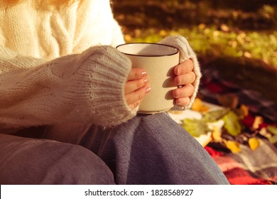 girl in a warm white sweater holds Cup of coffee. Autumn background, the concept of warmth and comfort