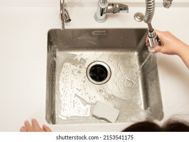 The Girl Washes Away The Foam In The Kitchen Sink From The Sprayer Faucet