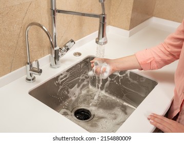 The Girl Washes Away The Foam In The Kitchen Sink From The Sprayer Faucet