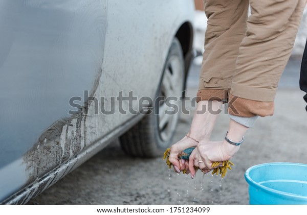 A girl washes a\
car. To wash the car with a sponge. Foam by car. Clean car. Squeeze\
a sponge with foam