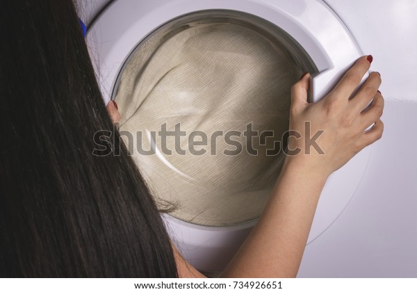 A girl washes\
clothes in the washing\
machine
