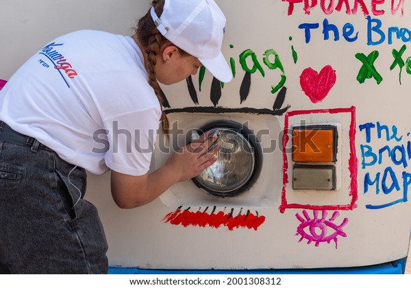 The girl washes the headlight of\
the bus from the drawings. Russia, Sterlitamak.\
27.06.2021