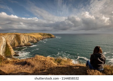 Girl watching the beautiful scenery of the cliffs of the Old Head of Kinsale, co. Cork, Ireland