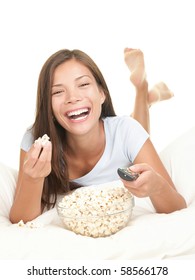 Girl Watching Movie / TV Laughing Having Fun Eating Popcorn In Bed. Young Mixed Asian / Caucasian Woman Model On Lying Down In Bed.