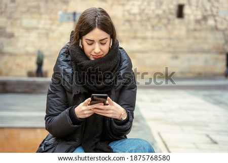 Girl watching a phone on street smiling