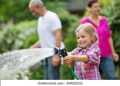 Girl-Wasserpflanzen im Garten, Familie auf Hintergrund