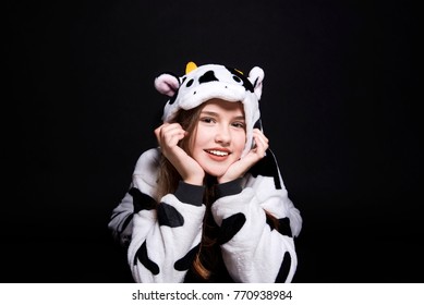 Girl Is Wearing Animal Pajamas. Merry Christmas And Happy Holidays Concept. Family Holiday, Party Over Black Background. Cute Teenage Girl. Child Is Lying. Happy Smile Lady. Cow Costume. 