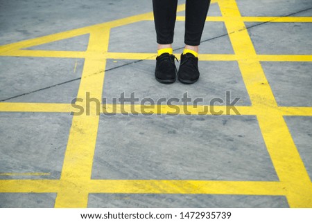 The girl wearing black trousers Yellow sock And black shoes Walk in the parking area With lifestyle and vintage background images.