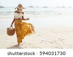 Girl wearing floral maxi skirt walking barefoot on the sea shore, Thailand, Phuket. Bohemian clothing style.