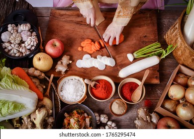 Girl wearing hanbok, making chopped kimchi, radish and carrots to mix with Chinese cabbage. Korean food concept from folk wisdom