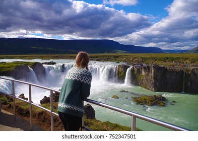 Girl wearing Icelandic sweater at the Goðafoss waterfall in Iceland