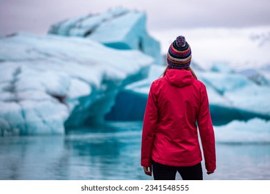 A girl wearing an Icelandic wool cap admires the unique blue icebergs on Lake Jökulsárlón, a unique glacial lake at the Vatnajökull glacier	