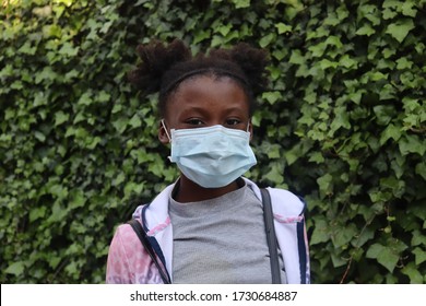 Girl wearing mask outdoors with green leaves from bushes in background - Powered by Shutterstock