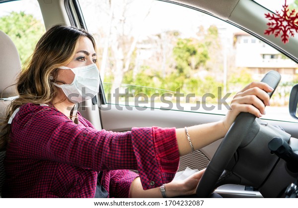 Girl wearing medical mask in the\
car for covid-19. Mask must be put on in everyday\
activities.