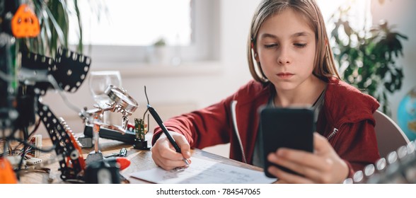 Girl Wearing Red Hoodie Using Smart Phone To Check Electrical Schematic At Home As A School Science Project