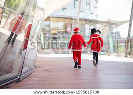 A girl wearing a sandy outfit and a boy wearing a Santa outfit are playing happily.