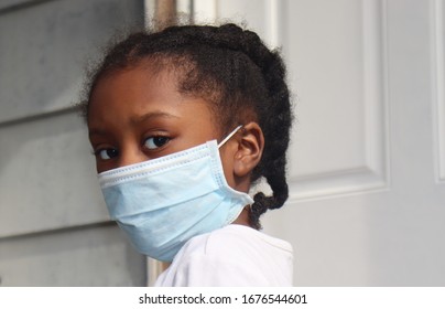 Girl Wearing surgical mask standing on house back porch with white door