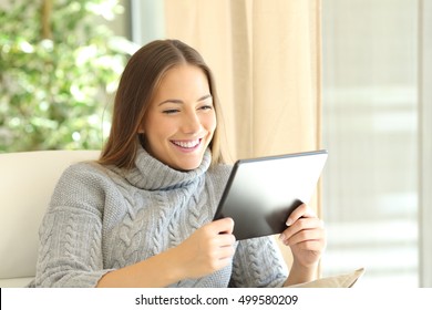 Girl Wearing Sweater Using A Tablet On Line At Home Sitting On A Couch In The Living Room At Home In Winter