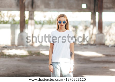 Girl wearing t-shirt and glasses posing against street , urban clothing style. Street photography