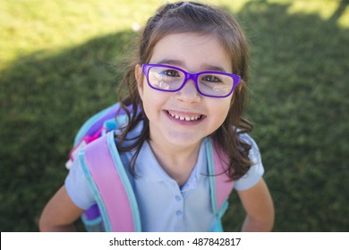 A Girl Wearing A Uniform And A Backpack Is Ready For Her First Day Of School.