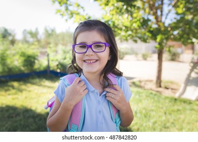 A Girl Wearing A Uniform And A Backpack Is Ready For Her First Day Of School.