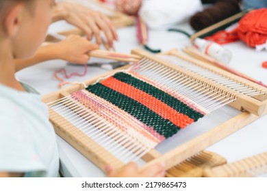 Girl Weaving Small Rug With Pattern At Masterclass On Weaving. Girl Is Studying How To Weave On Manual Table Loom. Process Of Creation. Handmade Concept