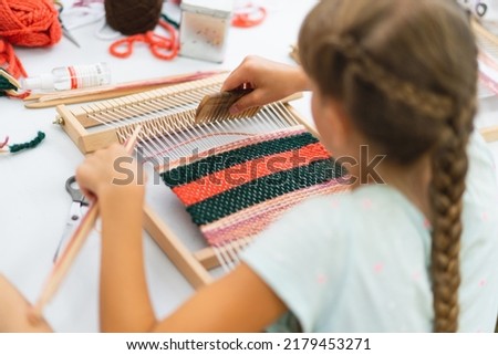 Girl weaving small rug with pattern at masterclass on weaving. Girl is studying how to weave on manual table loom. Process of creation. Handmade concept Photo stock © 