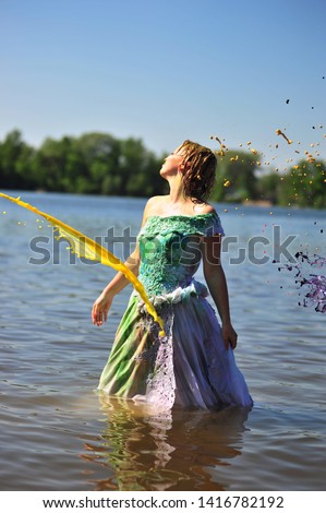 The girl in a wedding dress standing in water poured by a paint