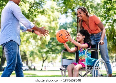 Girl In A Wheelchair Playing Basketball With Her Family.