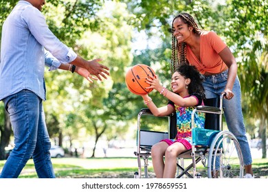 Girl In A Wheelchair Playing Basketball With Her Family.