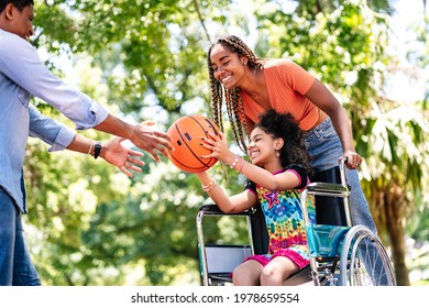 Girl In A Wheelchair Playing Basketball With Her Family.