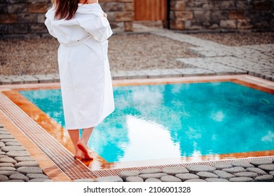 A girl in a white coat, near the pool with hot thermal water.
