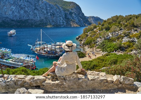 Girl in white dress and hat watching panorama from Kameriye Island or Kamelya Island on Aegean Sea. Island is one of most beautiful destinations of boat trips in Marmaris, Turkey. 