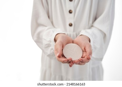 Girl in white dress holding a communion wafer