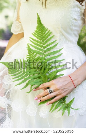 girl in a white dress, holding a green fern leaves in the forest