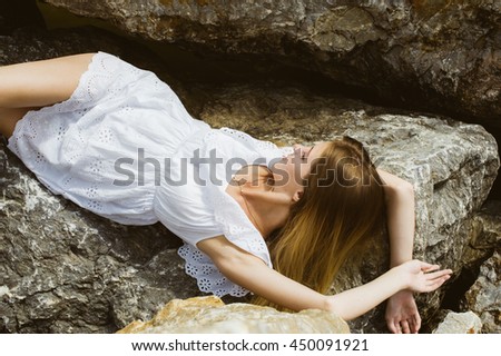 girl in white dress lying on the rocks