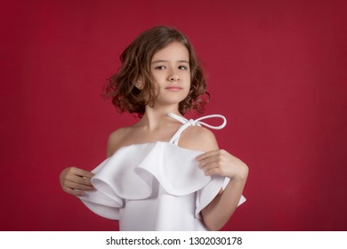 
A Girl In A White Dress. The Manifestation Of Emotions In A Child. Plain Background.