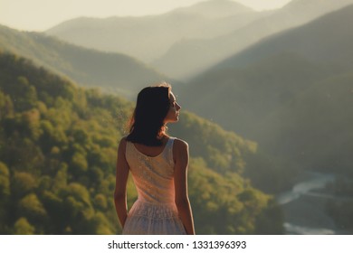 Girl in white dress standing back the top Caucasus mountain and scenery view to sunset at green valley and river  Female travel nature concept 