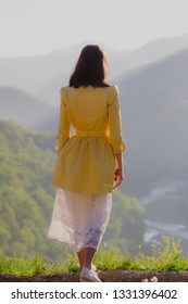 Girl in white dress standing back the top Caucasus mountain and scenery view to sunset at green valley  Female travel nature concept 