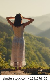 Girl in white dress standing back the top Caucasus mountain and scenery view to sunset at green valley  Female travel nature concept 