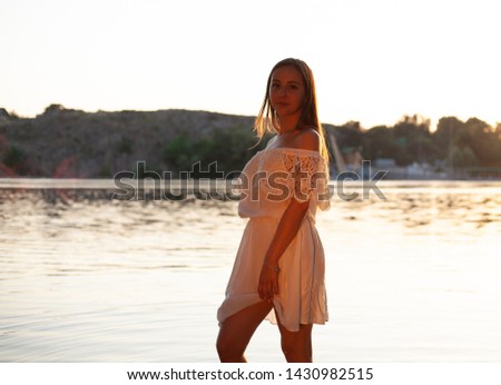 A girl in a white dress. In the water at sunset.