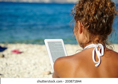 Girl With White Hat Reads Kindle On Beach 