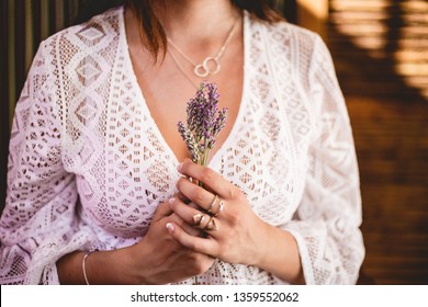 Girl in white lace crochet shirt holding a bouquet of lavender with circle silver necklaces