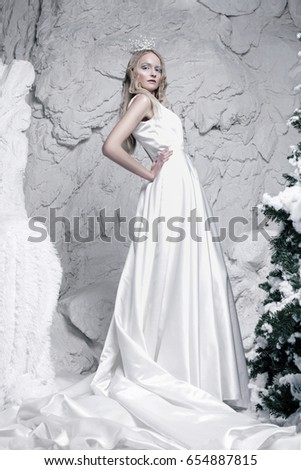 girl with white makeup in white dress standing in ice cave
