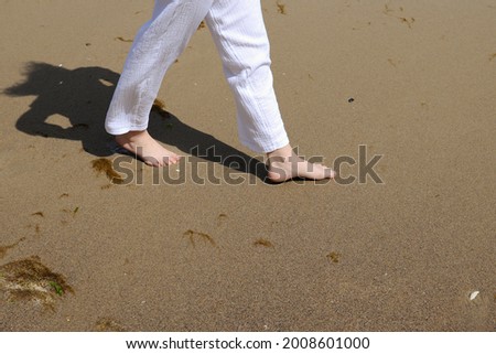 girl in white pants walks wide on the beach