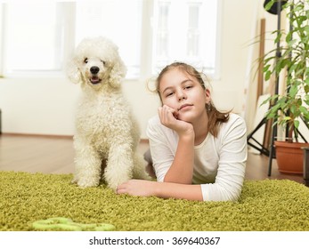 Girl With White Poodle Playing On The Green Carpet