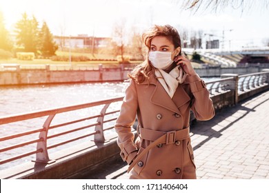 A girl in a white protective mask walks in the park. The epidemic of coronavirus. Protection from Covid-19