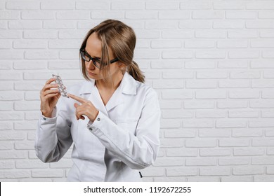 A girl in a white robe holds a medication in her hand and a second hand shows them on a white background - Powered by Shutterstock